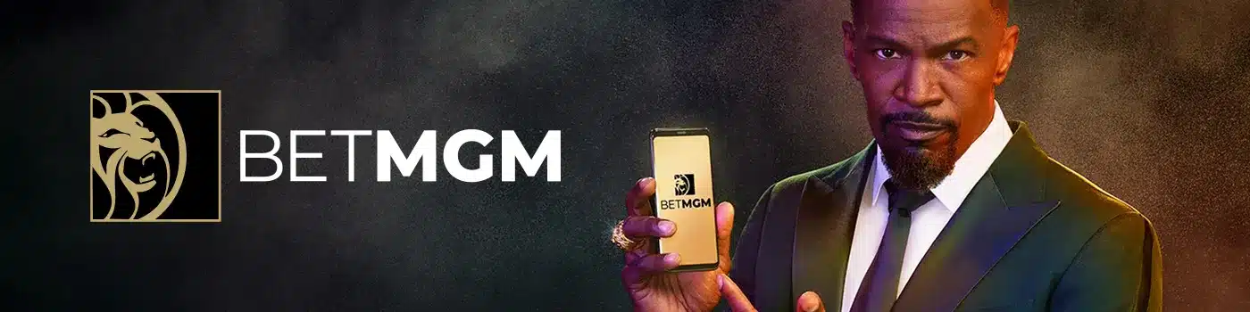 BetMGM desktop banner featuring an elegant man holding a smartphone displaying the sportsbook platform
